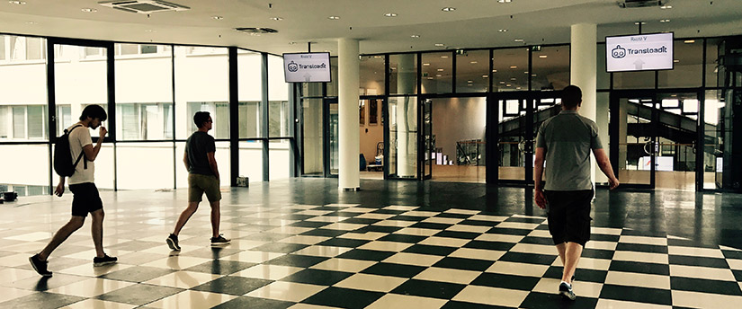 The team walking into a conference room with the Transloadit logo on TVs above.