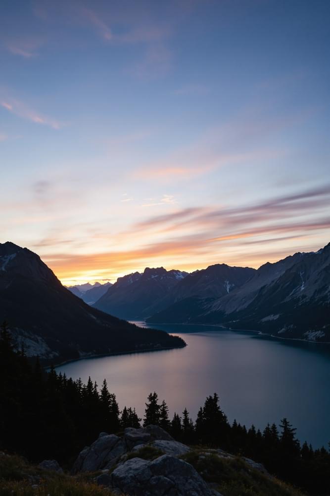 A serene landscape with mountains and a lake at sunset.